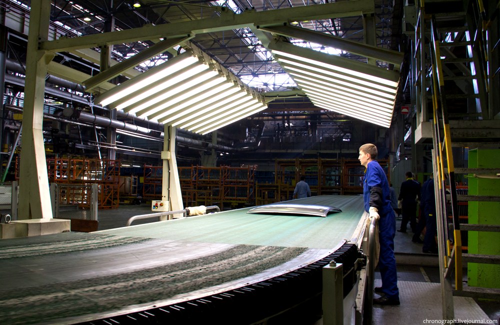 The press stamps roofs, and the worker checks its quality.